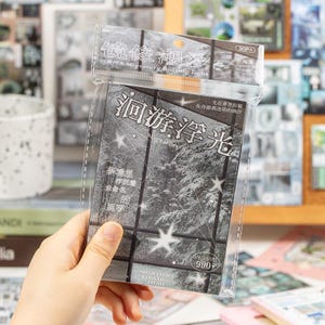 May include: A clear plastic package containing a set of stickers. The stickers feature a grayscale image of a snowy forest scene with the text "Migratory Floating Light" and other Chinese characters. The package also includes the text "30PA" and "990+".