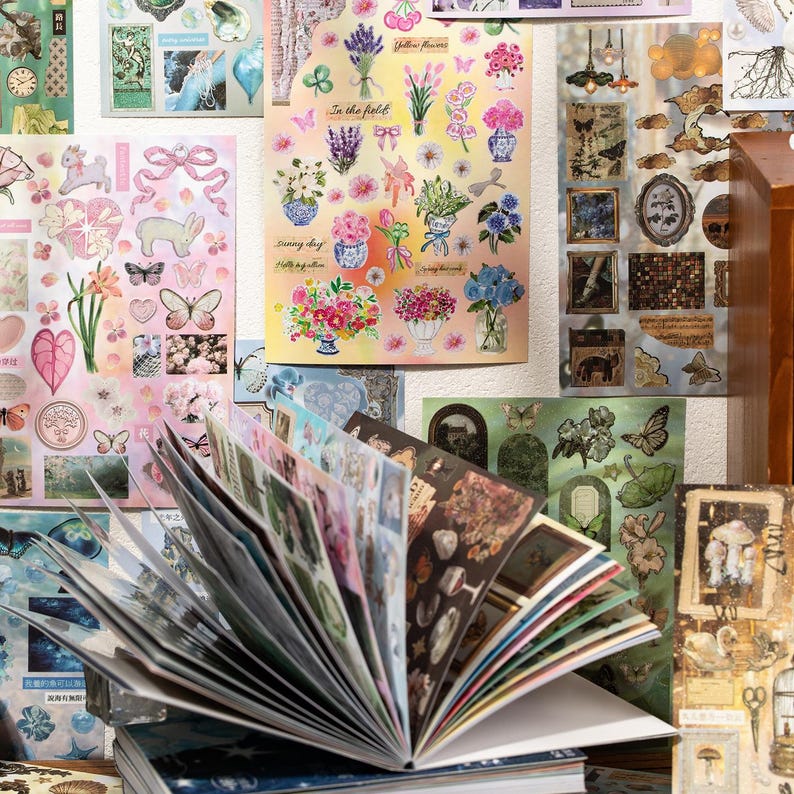 May include: A collection of decorative stickers and a journal. The stickers feature floral designs, butterflies, and other nature-inspired elements. The journal is open, displaying various sticker sheets with diverse illustrations and colors.