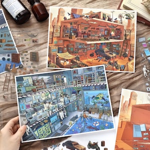 May include: Two rectangular art prints featuring detailed, multi-level cross-section illustrations. One print depicts a desert-toned post-apocalyptic hideout with a garage and living space, while the other shows a blue-toned underwater research laboratory.