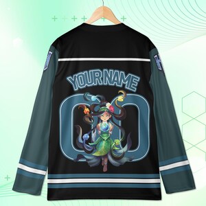 May include: Black long-sleeved jersey with teal and white accents. The jersey features the text "YOUR NAME" above a teal number "0" with a cartoon illustration of a girl holding a glowing orb. The sleeves are teal with white stripes.