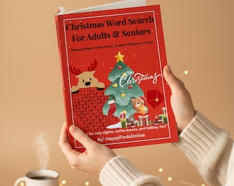 May include: A red Christmas word search book for adults and seniors. The cover features a Christmas tree, reindeer, and teddy bear illustrations. The book is held by a person wearing a cream-coloured sweater.