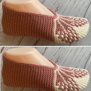 Puede incluir: Zapatilla tejida a mano en color rosa empolvado con un patrón geométrico crema en la puntera. La zapatilla se muestra en una forma de pie, mostrando el diseño y la construcción. La textura tejida es visible.