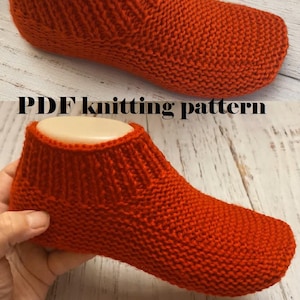 Puede incluir: Un calcetín de pantufla rojo tejido, exhibido en una horma de pie. El calcetín es de un tono rojo vibrante, con un puño acanalado y un patrón de tejido texturizado. El texto "PDF knitting pattern" está en la imagen.