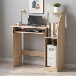 May include: A light wood-grain computer desk featuring a pull-out keyboard tray, a top shelf, and a side storage unit with two open compartments. The desk holds a laptop, a gold desk lamp, a white mug, and a white computer tower case.