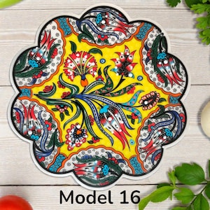 May include: A decorative, floral-patterned trivet with a scalloped edge. The trivet features a yellow background with red, blue, and green floral designs. The text "Model 16" is printed at the bottom.