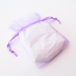 May include: A small, lavender-colored organza bag with a white drawstring. The bag is empty and ready to be filled with a small gift.