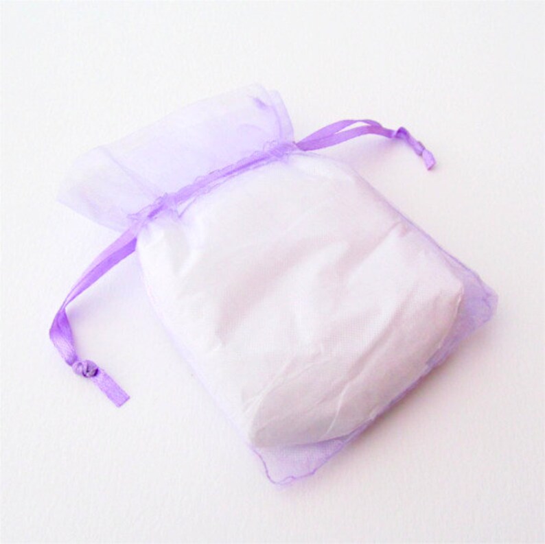 May include: A small, lavender-colored organza bag with a white drawstring. The bag is empty and ready to be filled with a small gift.