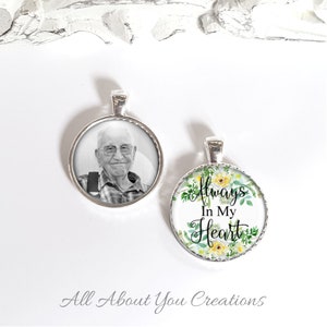 May include: Two silver pendant necklaces. One features a black and white photo of an older man. The other has a floral design with the text "Always In My Heart".