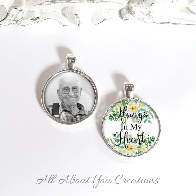 May include: Two silver pendant necklaces. One features a black and white photo of an older man. The other has a floral design with the text "Always In My Heart".
