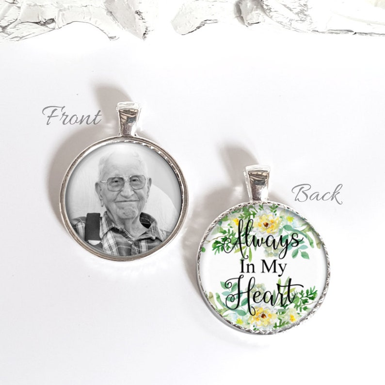 May include: A silver pendant with a photo of an older man on the front and the words "Always In My Heart" with a floral design on the back.