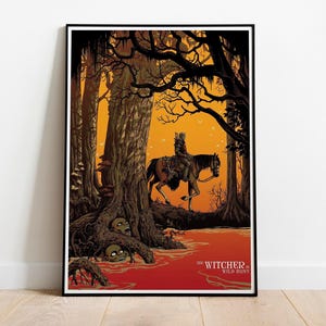 May include: Framed poster featuring a scene from "The Witcher: Wild Hunt." A figure on horseback rides through a dark forest with an orange sky. The poster has a black frame and is displayed on a wooden floor.