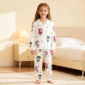 May include: White pajama set featuring cartoon characters and star patterns. The long-sleeved top has a button-down front and a collar. The matching pants have an elastic waistband. The pajamas are designed for children.