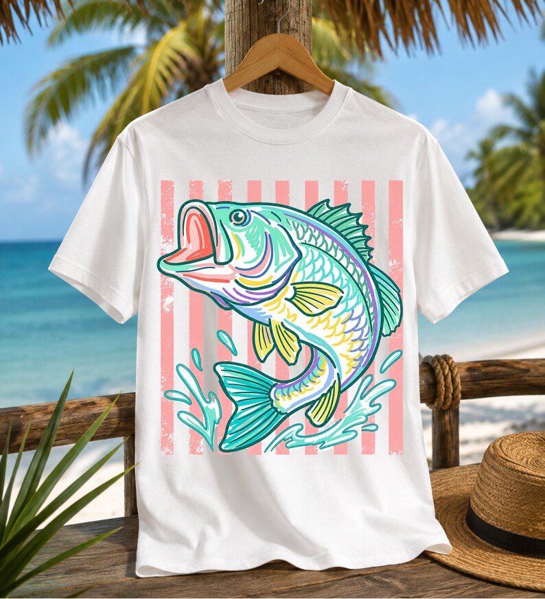 May include: White t-shirt featuring a colorful illustration of a fish with an open mouth, splashing water, and a pink striped background. The fish has teal, yellow, purple, and green details. The shirt is hanging on a wooden hanger.
