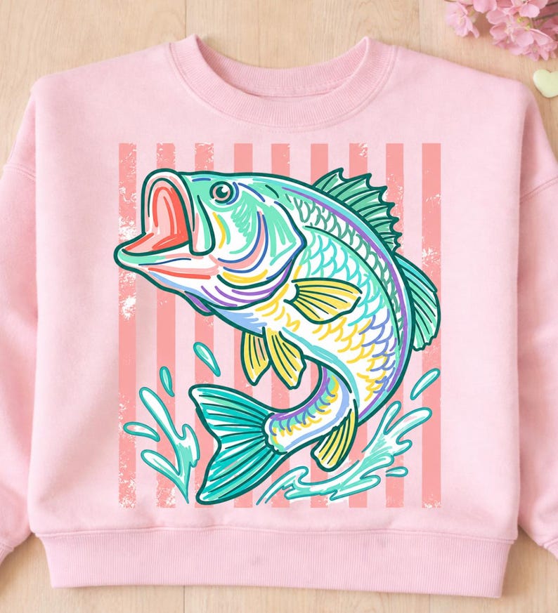 May include: A light pink sweatshirt featuring a colorful illustration of a leaping fish. The fish is depicted in shades of teal, yellow, purple, and green, with water splashes and a striped background. The design has a vintage, hand-drawn aesthetic.