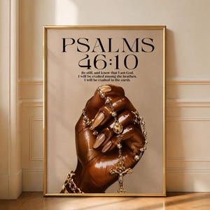 Puede incluir: Impresión enmarcada con el texto «PSALMS 46:10» y una cita. La imagen muestra una mano sosteniendo un rosario dorado con un crucifijo. La mano tiene uñas largas y pulidas y una pulsera dorada. Fondo neutro.