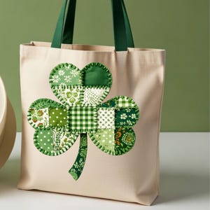 Könnte beinhalten: Beige Canvas-Tragetasche mit einem großen, applizierten Kleeblatt-Design. Das Kleeblatt besteht aus verschiedenen grün gemusterten Stoffen, darunter Punkte, Vichy-Karo und Blumendrucke. Die Tasche hat grüne Griffe und einen grünen Stiel am Kleeblatt.