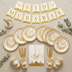 Op de afbeelding: Een feestelijke Eid Mubarak-feestset met gouden en witte decoraties. Inclusief borden, bekers, rietjes, servetten en een banner. De borden en bekers hebben een maansikkelontwerp. De banner luidt "Eid Mubarak".
