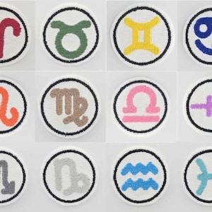Op de afbeelding: Een verzameling van twaalf ronde, witte onderzetters, elk met een verschillend sterrenbeeld. Elke onderzetter heeft een zwarte rand en een witte achtergrond, met symbolen in rood, groen, geel, blauw, oranje, bruin, roze, paars, grijs en turquoise.