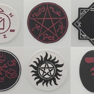 Puede incluir: Un conjunto de seis parches bordados con varios símbolos. Incluyen un círculo blanco con un símbolo granate, un pentagrama negro con detalles granates y un parche negro en forma de estrella con ribete blanco.