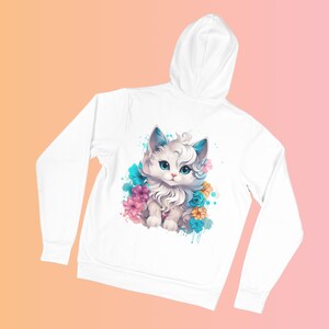 May include: White hoodie featuring a watercolor illustration of a fluffy white cat with blue and pink accents, surrounded by flowers. The cat has blue eyes and ears. The hoodie has a drawstring hood and long sleeves.