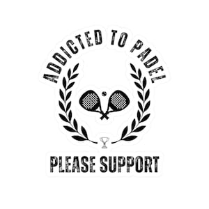 以下が含まれることがあります： 白いステッカー。上部に「ADDICTED TO PADEL」の文字がアーチ状に配置され、交差したパデルラケットとテニスボール、月桂樹の冠が描かれています。「PLEASE SUPPORT」の文字が下にあります。