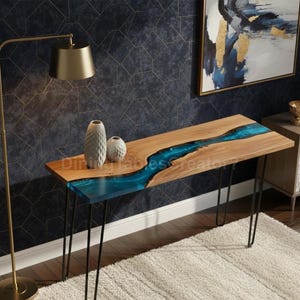 Puede incluir: Una consola de madera con un río de resina azul en el centro. La mesa tiene patas de horquilla negras y está decorada con dos jarrones blancos. La mesa mide aproximadamente 152 cm de largo.