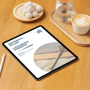May include: A digital tablet shows the title "Sentimental Styling: A Downsizing Workbook" with a house logo. A white stylus, a wooden tray with coconut candies, and a coffee cup with latte art are also visible.