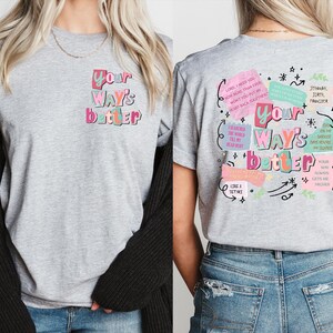 May include: A heather gray t-shirt with the text "Your Way's Better" in colorful bubble letters. The back of the shirt features additional text and graphics in a similar style, including phrases like "Lord, I need you" and "Your way always gets me higher."