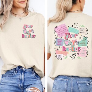 May include: Cream-colored t-shirt with the text "Your Way's Better" in colorful, stylized lettering on the front and back. The back features additional text and graphics in a similar style, including phrases and arrows.