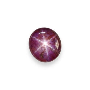Può includere: Una gemma di rubino stellato di forma rotonda, tagliata a cabochon, con una profonda tonalità magenta-viola. La superficie mostra un distinto effetto a stella a sei raggi, noto come asterismo, che si irradia dal centro della pietra lucida.