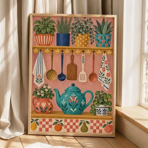 May include: A rectangular wall art print featuring a kitchen scene with potted plants on a shelf, hanging kitchen utensils, two patterned towels, a central teal teapot with floral motifs, and a bottom border of fruit and red and white tiles.