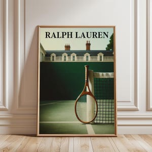 May include: Framed print featuring a vintage tennis racket leaning against a net on a green court. The print has the text "RALPH LAUREN" at the top. The background shows a building with a white facade and a green wall.