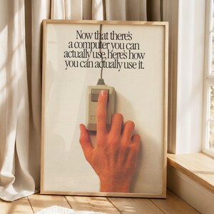 Könnte beinhalten: Ein gerahmtes Vintage-Werbeposter mit einer beigen Computermaus mit einer Taste, die von einem Finger gedrückt wird. Der Text lautet: Now that there's a computer you can actually use, here's how you can actually use it.