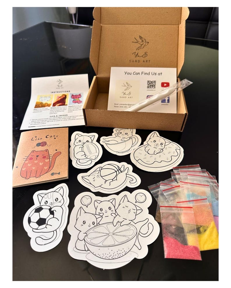 Puede incluir: Un kit de arte con arena que incluye una caja de cart&oacute;n marr&oacute;n, una hoja de instrucciones, un peque&ntilde;o folleto titulado Like Cats y varios contornos adhesivos de gatos. El set contiene un l&aacute;piz blanco y bolsas con arena de colores.