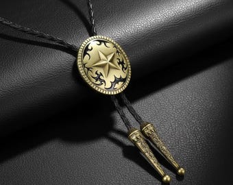 May include: A bolo tie with a gold-colored starburst design on a circular pendant. The pendant has a black decorative border and is attached to a black braided cord with decorative gold-colored tips. The background is a textured black surface.