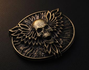Puede incluir: Hebilla de cinturón de estilo antiguo con diseño de calavera y alas estilizadas. La hebilla con acabado bronce se encuentra sobre un fondo oscuro. El diseño de la hebilla es muy detallado.