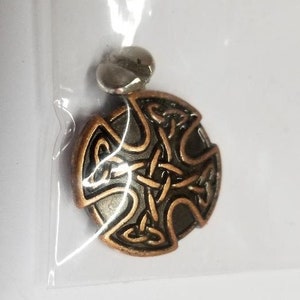 May include: A copper-colored Celtic knot pendant with a silver bail. The knot is a traditional design with intricate details.