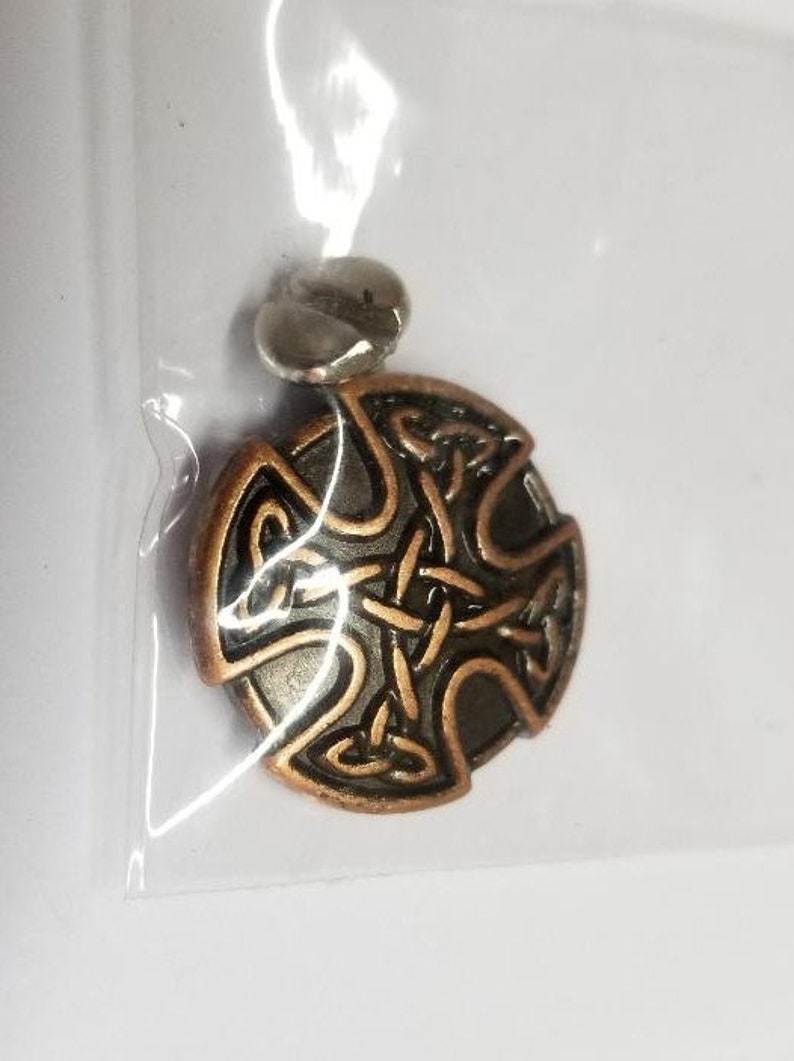 May include: A copper-colored Celtic knot pendant with a silver bail. The knot is a traditional design with intricate details.
