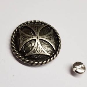Op de afbeelding: Zilveren metalen knoop met een kruisontwerp en een touwrand. De knoop wordt geleverd met een schroef om hem aan stof te bevestigen.