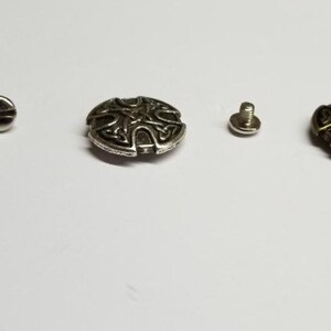 May include: Three metal Celtic knot buttons with screws. The buttons are in copper, silver, and antique gold.