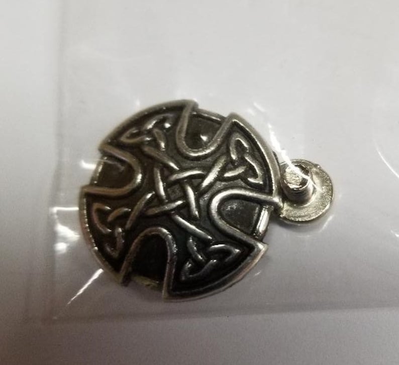 May include: A silver Celtic knot pendant with a black background. The pendant is round and has a loop at the top for attaching to a chain.