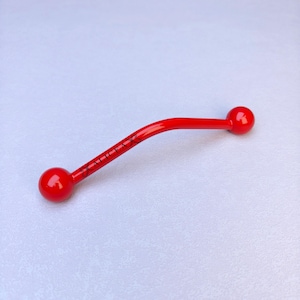 May include: A curved red barbell body jewelry piece featuring a smooth, glossy finish with spherical ends. The central bar is inscribed with the black text ALICEA in a stylized font, positioned between two small decorative butterfly-like symbols.