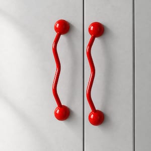 Pode incluir: Dois puxadores de armário vermelho brilhante com uma forma ondulada e serpentina distinta. Cada puxador apresenta um acabamento liso e brilhante e termina numa esfera nas extremidades superior e inferior, montados verticalmente.