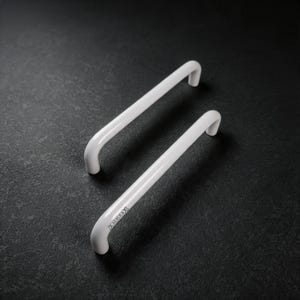 Puede incluir: Dos tiradores de armario cilíndricos, lisos y blancos, con un diseño curvado. El tirador delantero presenta el texto ALICEA grabado en su superficie. Estas piezas de herraje tienen un acabado brillante y una forma redondeada sencilla.