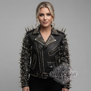 May include: Black leather jacket with silver spikes and studs. The jacket has a classic biker style with an asymmetrical zip, a notched collar, and a waist belt. The sleeves and shoulders are heavily adorned with metal spikes.