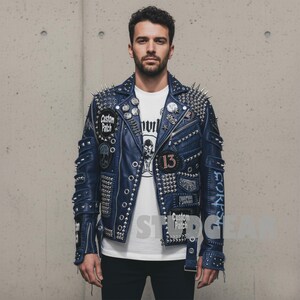 May include: A blue leather jacket with silver spikes and patches. The jacket has multiple patches with text and skull designs. The person is wearing a white t-shirt underneath. The jacket is a bold fashion statement.
