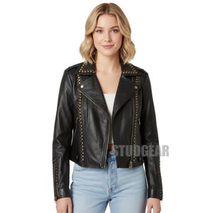 May include: Black leather jacket with gold-colored stud accents. The jacket has a classic biker style with a notched collar, asymmetrical zipper, and multiple pockets. The text "STUDGEAR" is visible on the jacket.