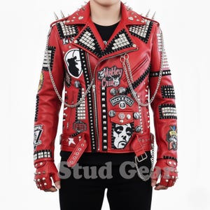 May include: A red leather jacket with silver studs, spikes, and patches. The jacket features a zipper closure, multiple pockets, and a chain detail. Patches include the text "Mötley Crüe" and "Rock N' Roll". Includes matching studded gloves.