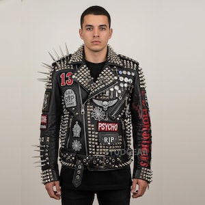 May include: Black leather jacket with silver studs and spikes. Patches include "13", "PSYCHO", and "RIP". The jacket has a zipper closure and a buckled belt. The sleeves and collar are heavily studded.