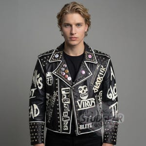 May include: A black leather jacket featuring silver metal studs along the lapels, shoulders, and cuffs. The jacket is decorated with white hand-painted text and graphics, including a skull icon, the words The Virus, Partisans, and Blitz.